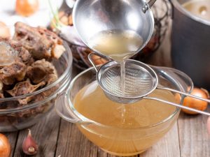 bone broth being poured into a cup