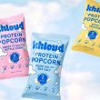 bags of khloud protein popcorn on a blue background with white clouds