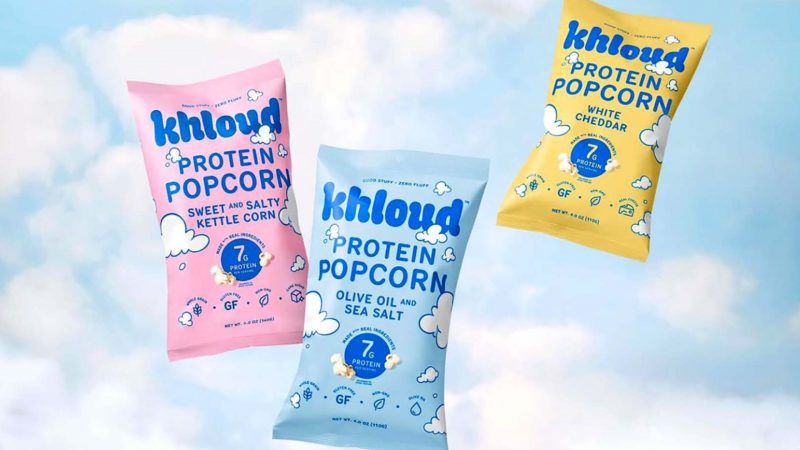 bags of khloud protein popcorn on a blue background with white clouds